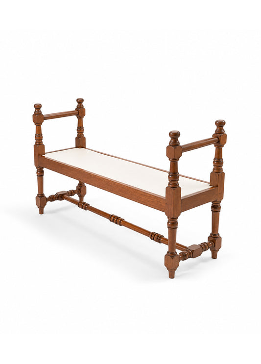 A wooden bench with turned spindle legs and a cream upholstered seat, shown on a clean white background.