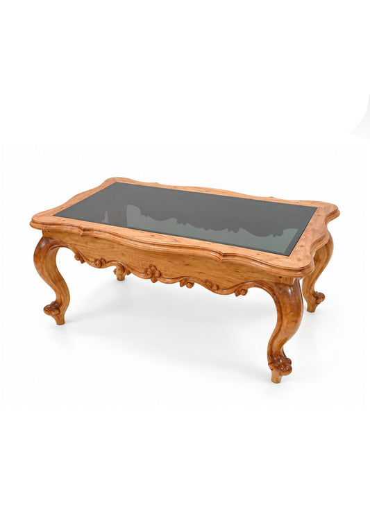An ornate wooden coffee table with a carved light brown wood frame and a dark glass top, shown on a plain white background.