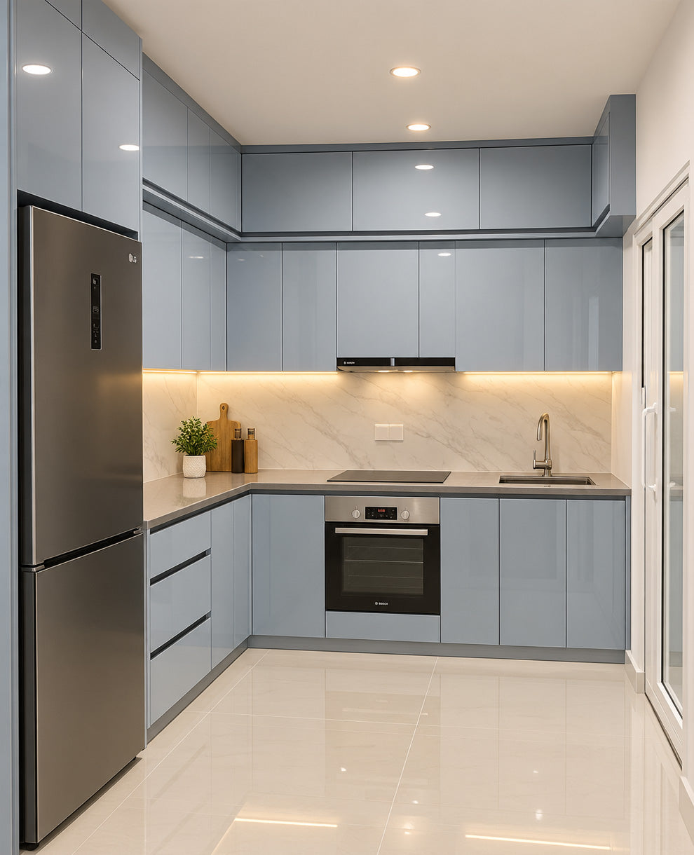 Modern L-shaped kitchen with light blue cabinets, stainless steel appliances including a refrigerator and built-in oven, a marble-look backsplash, and warm under-cabinet lighting.
