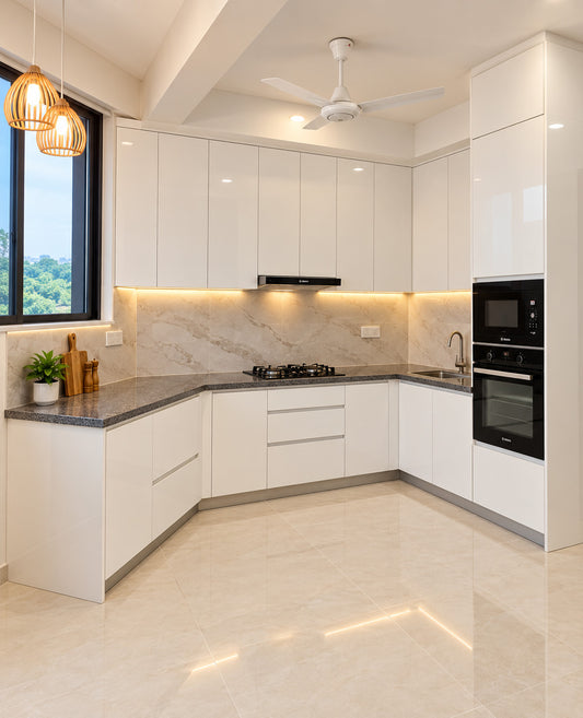 A modern L-shaped kitchen with glossy white cabinets, a light beige marble backsplash, dark gray stone countertops, built-in black appliances, pendant lights, and a ceiling fan.